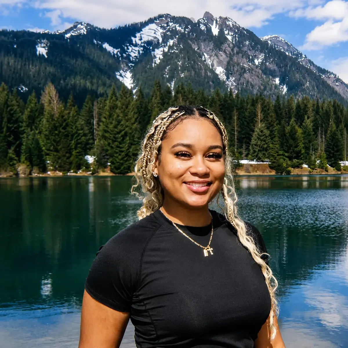 Jasmine Smith, certified full spectrum doula, smiling beside a mountain lake in Washington.